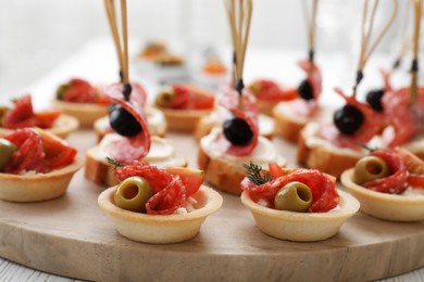 Photo of Many different tasty canapes on white wooden table, closeup