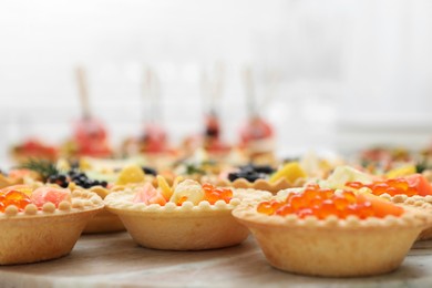 Photo of Many different tasty canapes on wooden board, closeup