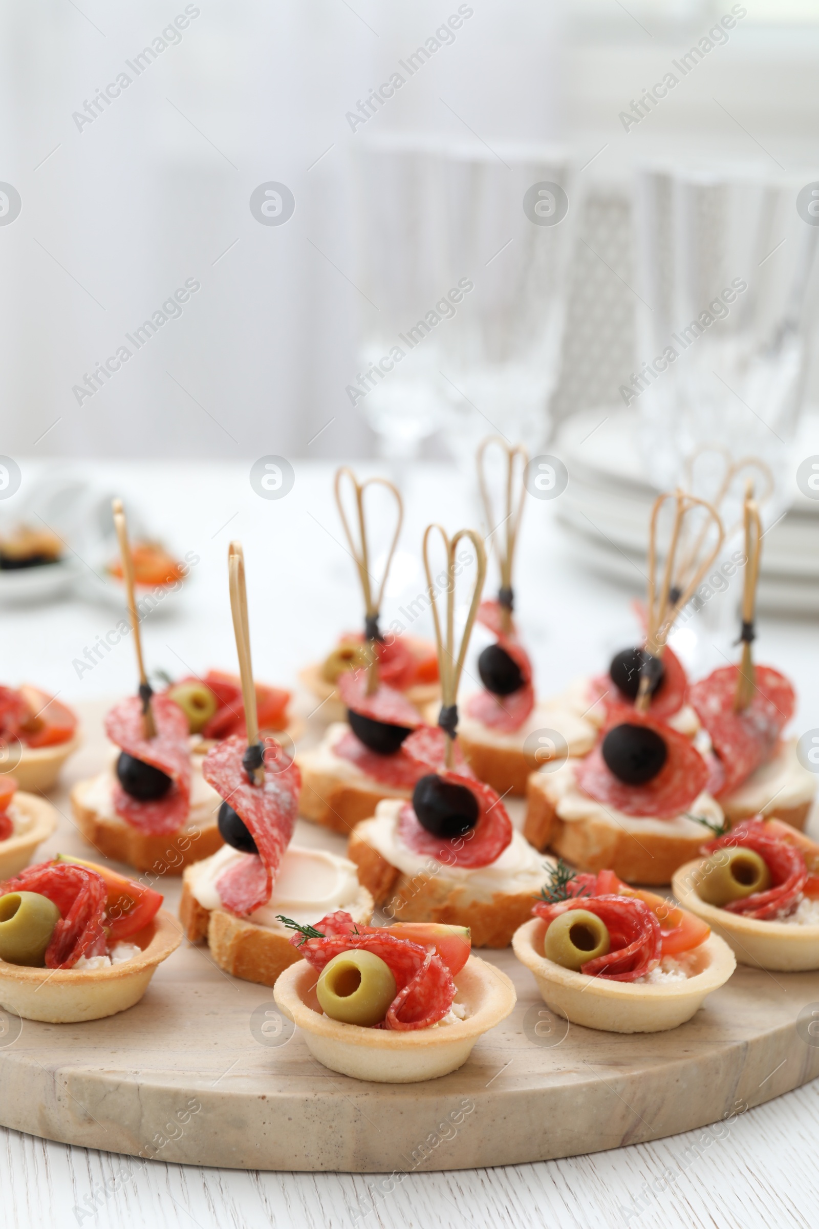 Photo of Many different tasty canapes on white wooden table, closeup