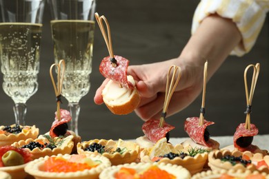 Photo of Woman taking tasty canape at table, closeup