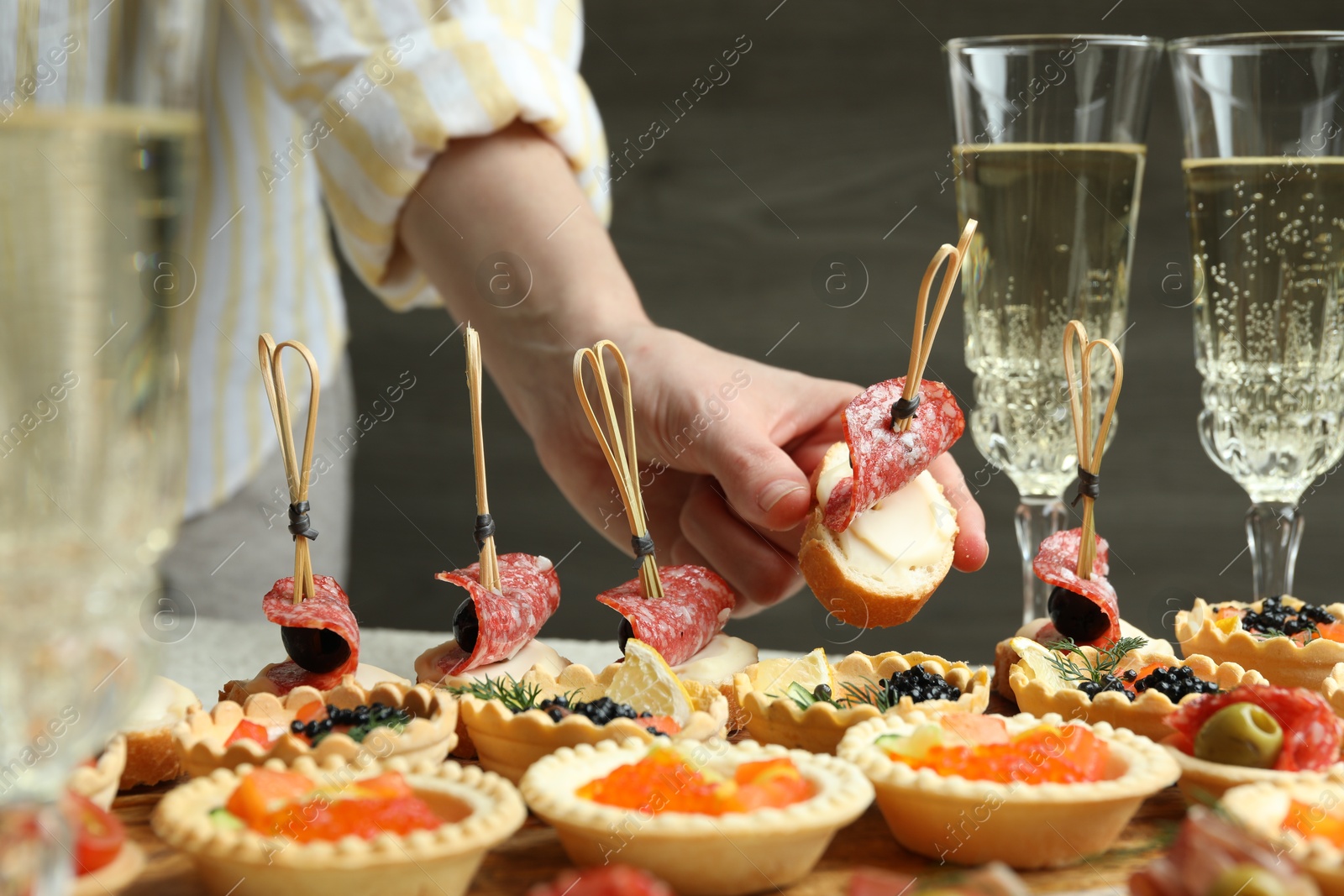 Photo of Woman taking tasty canape at table, closeup