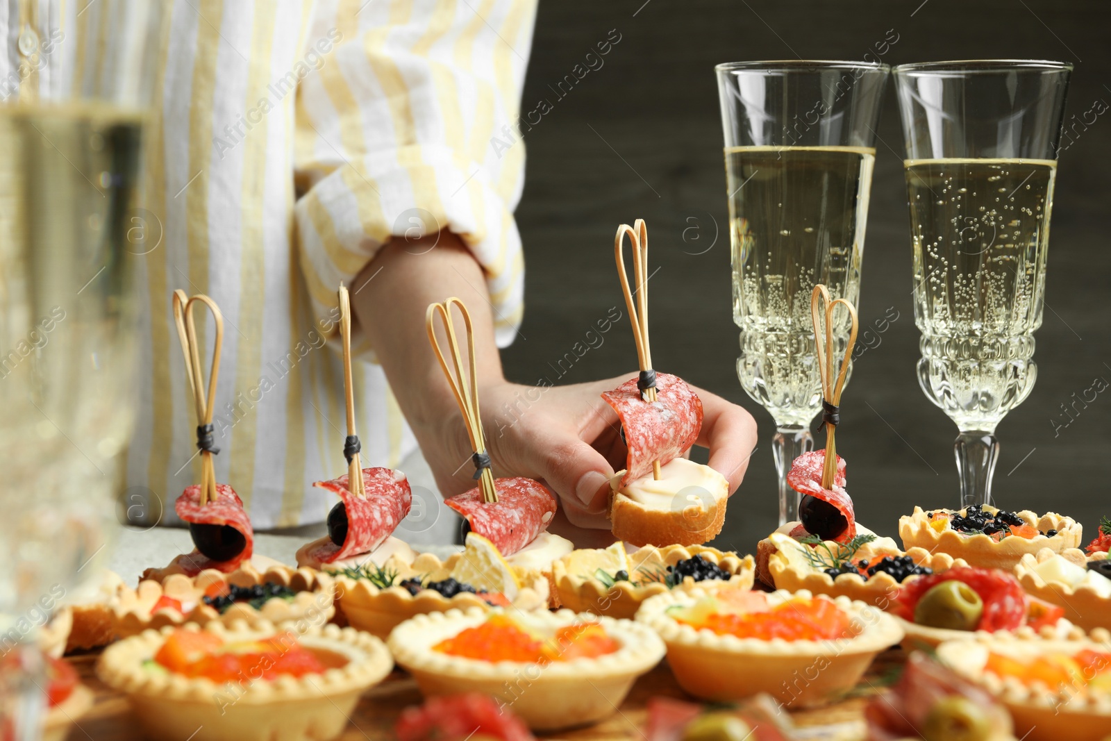 Photo of Woman taking tasty canape at table, closeup