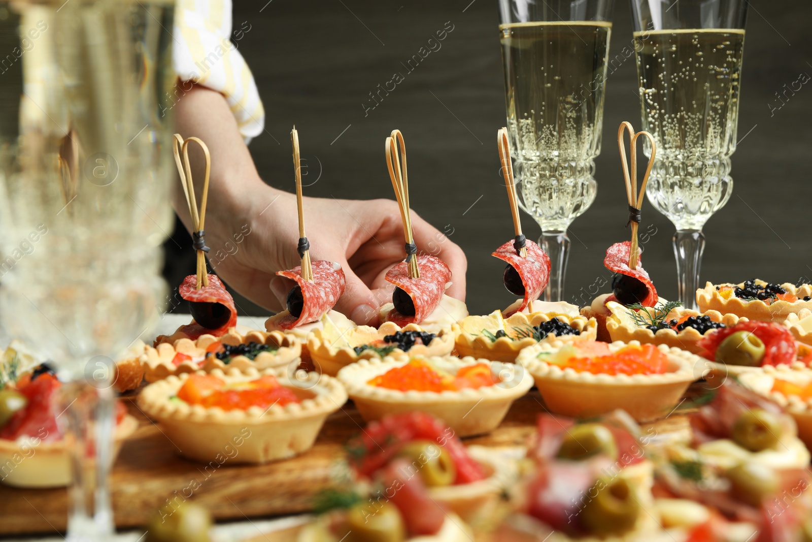 Photo of Woman taking tasty canape at table, closeup