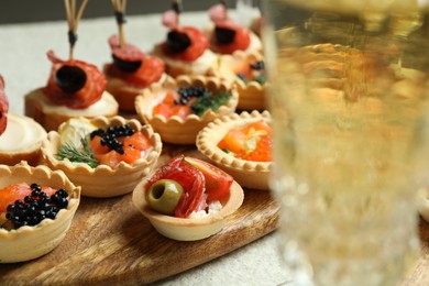 Photo of Many different tasty canapes and wine on white table, closeup