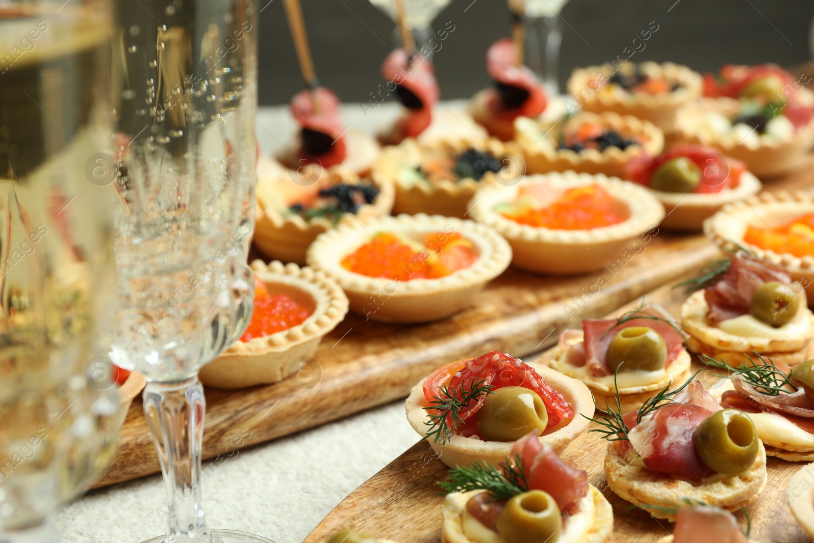 Photo of Many different tasty canapes and wine on white table, closeup