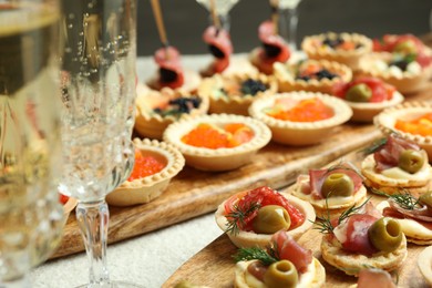 Photo of Many different tasty canapes and wine on white table, closeup