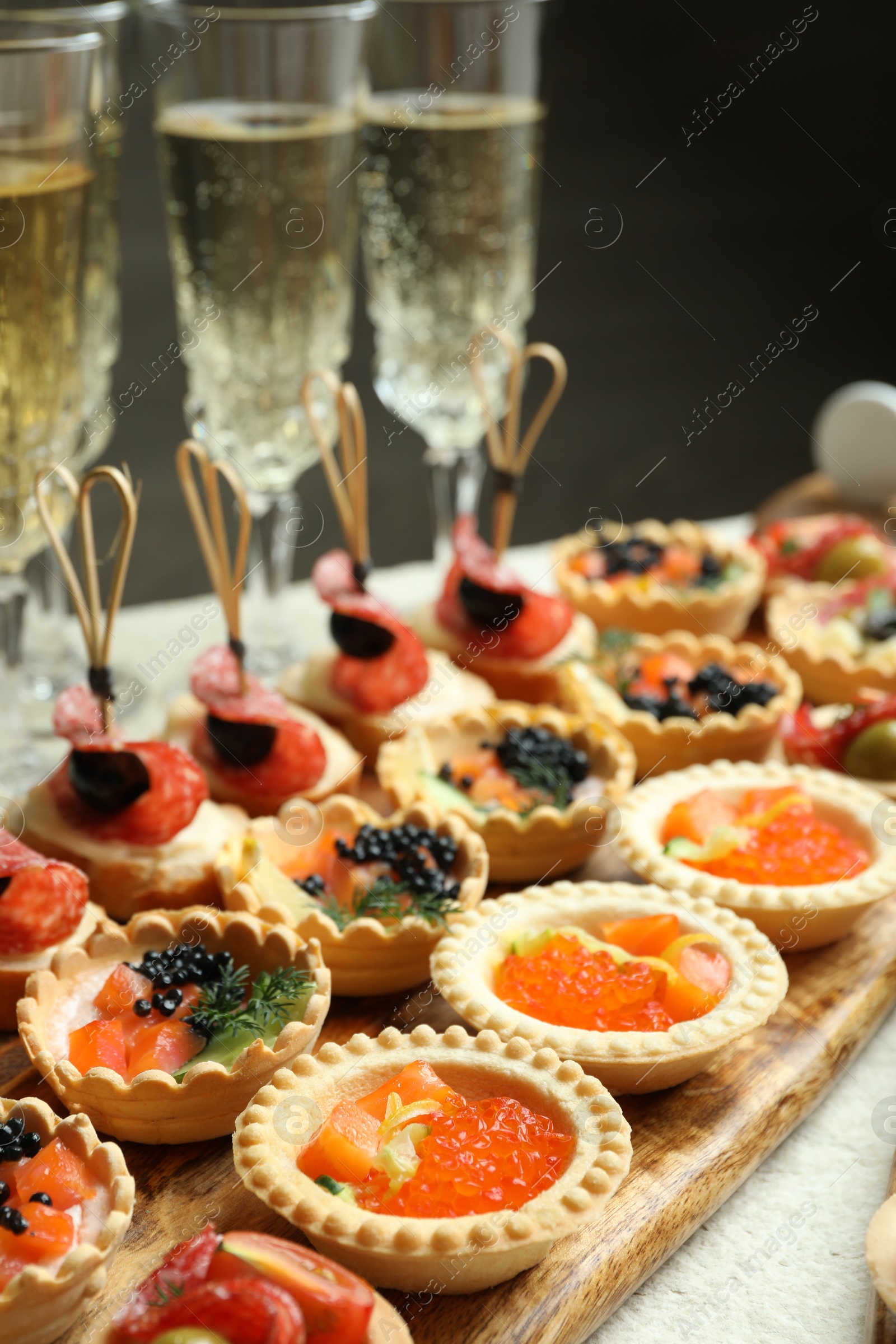 Photo of Many different tasty canapes and wine on white table, closeup