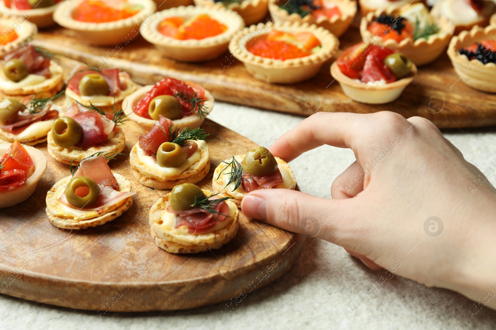 Photo of Woman taking tasty canape at white table, closeup