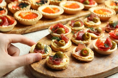 Photo of Woman taking tasty canape at white table, closeup