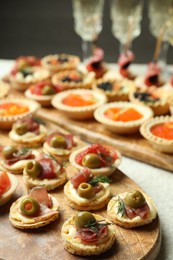 Photo of Many different tasty canapes and wine on white table, closeup