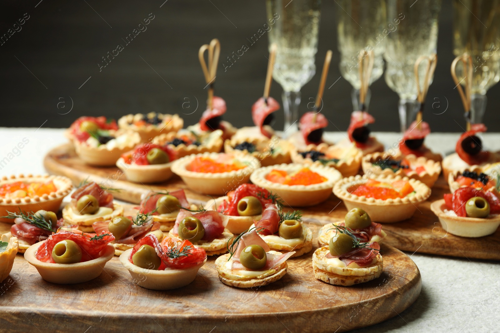 Photo of Many different tasty canapes and wine on white table, closeup