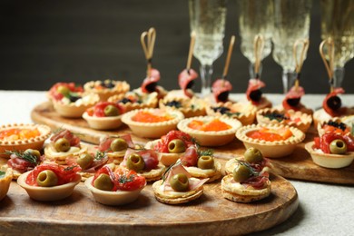 Photo of Many different tasty canapes and wine on white table, closeup