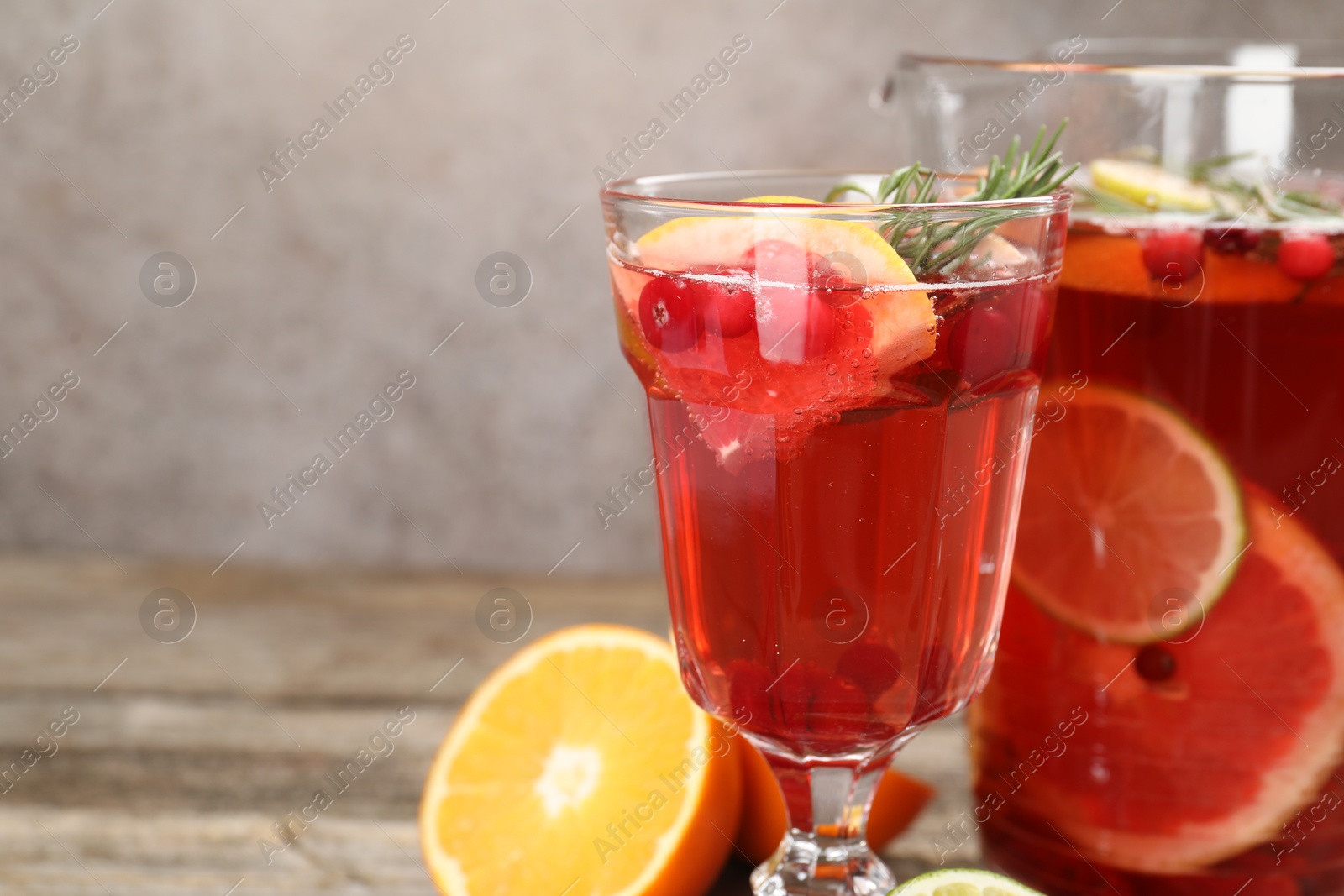 Photo of Aromatic punch drink in glass and jug on table, closeup. Space for text