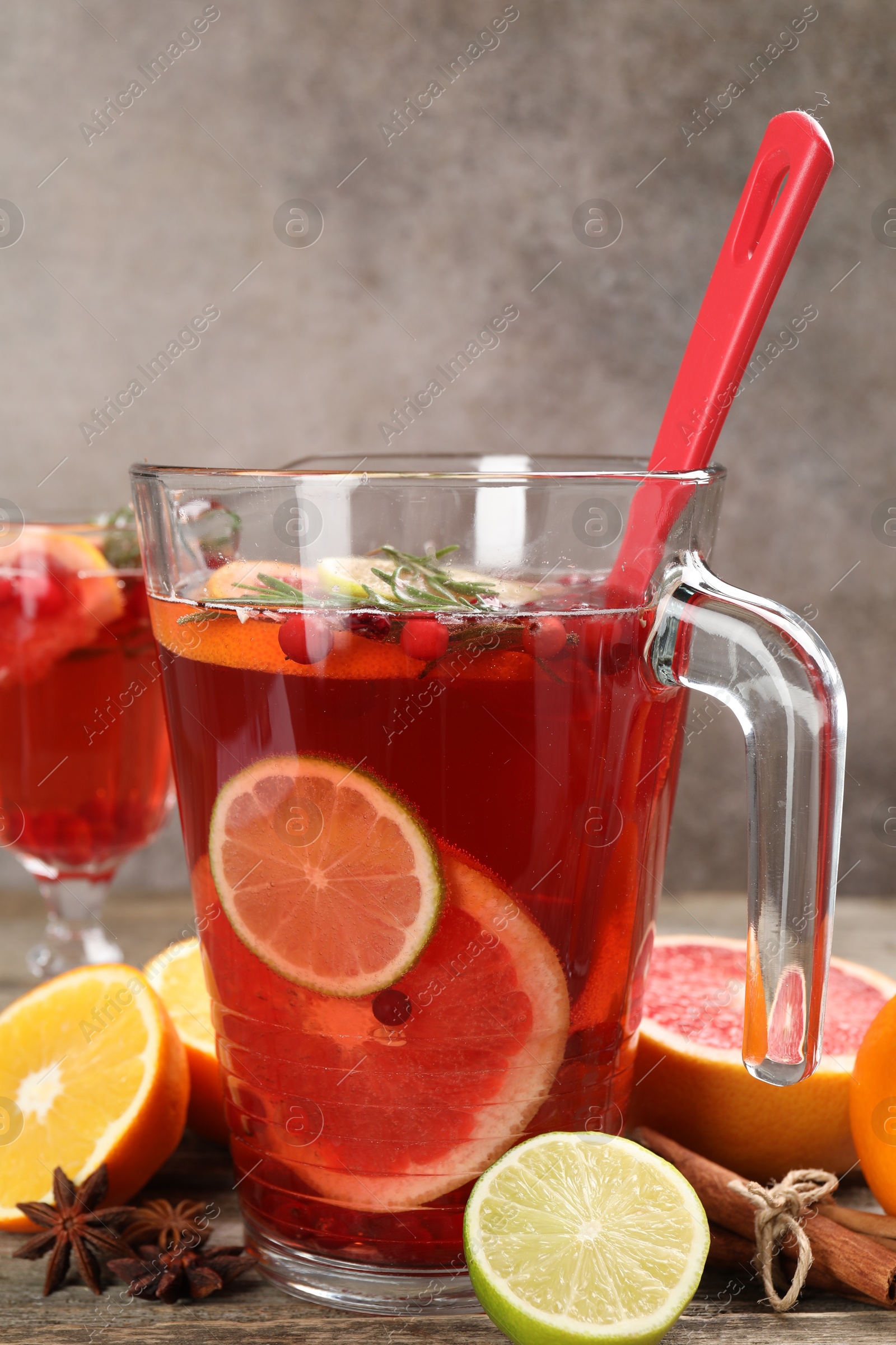 Photo of Aromatic punch drink in jug, fresh fruits and spices on wooden table, closeup