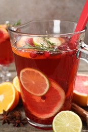 Photo of Aromatic punch drink in jug, fresh fruits and spices on wooden table, closeup