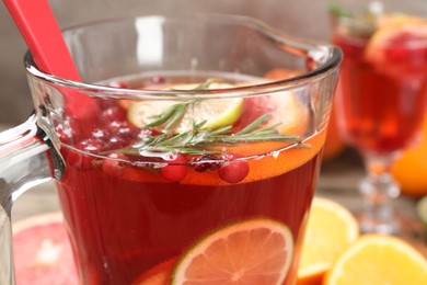 Photo of Aromatic punch drink in glass jug on table, closeup