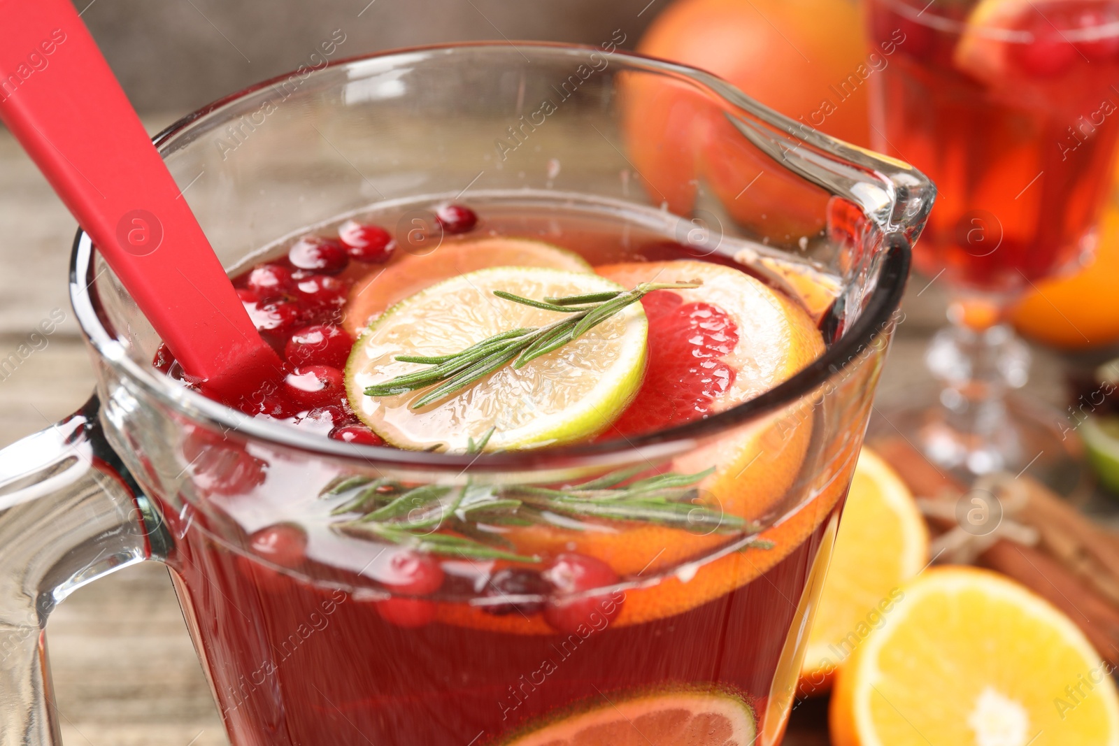 Photo of Aromatic punch drink in glass jug on table, closeup