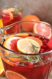 Photo of Aromatic punch drink in glass jug on blurred background, closeup