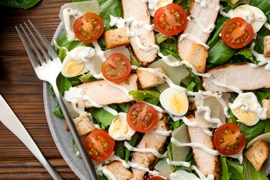 Photo of Delicious Caesar salad with chicken on wooden table, top view