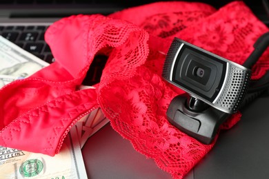 Photo of Sex work. Web camera, panties and money on laptop, closeup