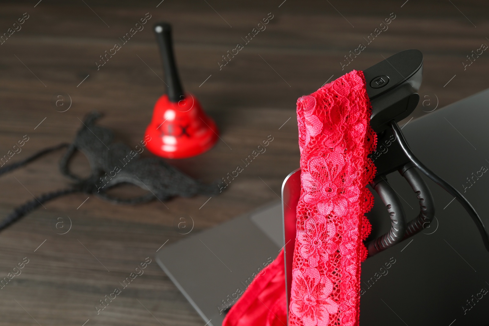 Photo of Sex work. Laptop with web camera and panties on wooden surface, closeup