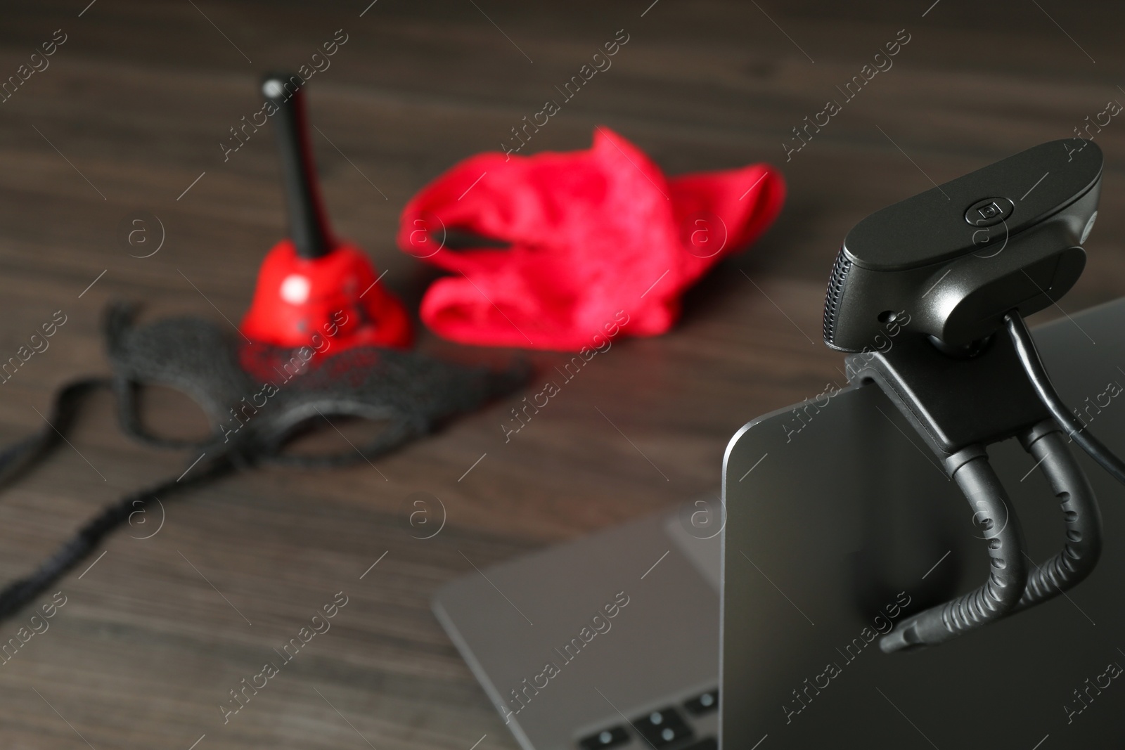 Photo of Sex work. Laptop with web camera on wooden surface, closeup