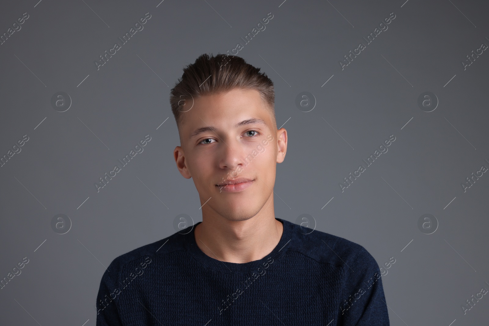 Photo of Handsome young man with stylish haircut on grey background