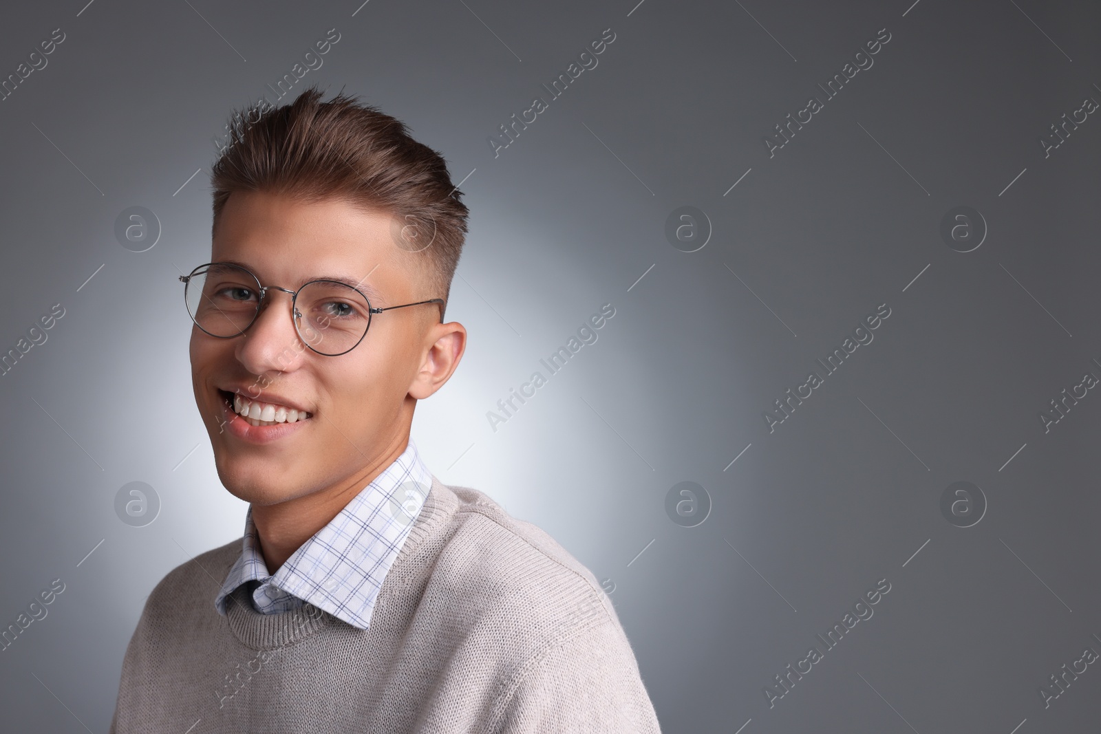 Photo of Handsome young man with stylish haircut on grey background. Space for text