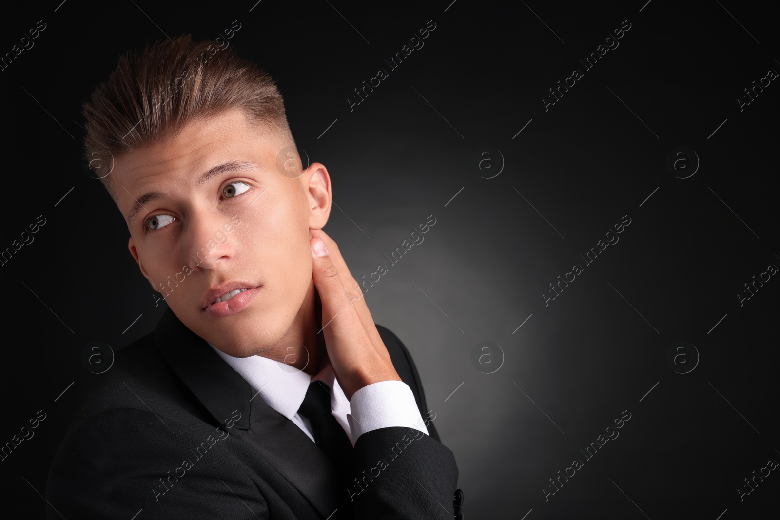 Photo of Confident young man with stylish haircut on black background. Space for text