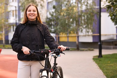 Photo of Smiling woman with bicycle outdoors. Healthy lifestyle