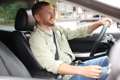 Photo of Happy man behind steering wheel of modern car