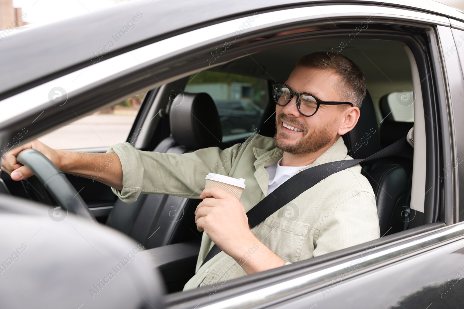 Photo of Man with cup of coffee driving modern car