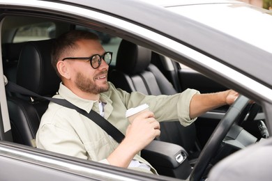 Photo of Man with cup of coffee driving modern car