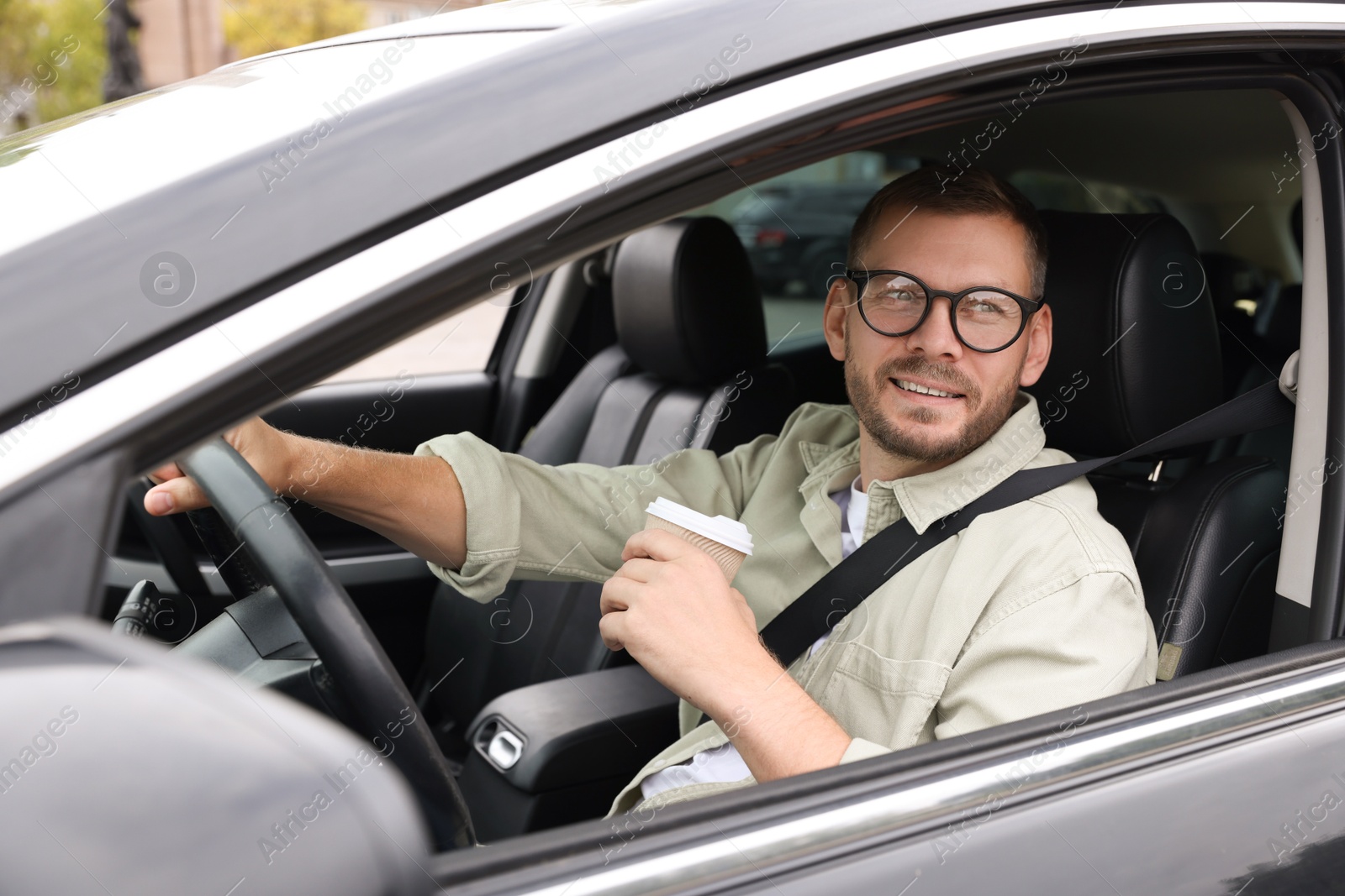 Photo of Man with cup of coffee driving modern car