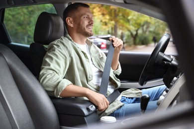 Photo of Man fastening seat belt in modern car