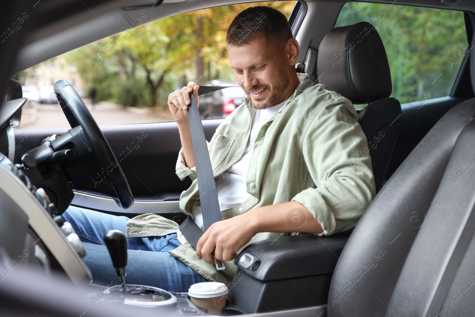 Photo of Man fastening seat belt in modern car