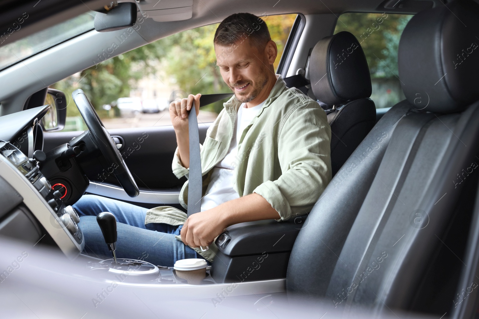 Photo of Man fastening seat belt in modern car