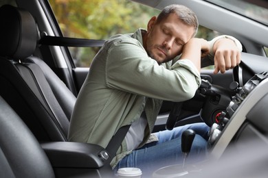 Photo of Tired man sleeping on steering wheel in car