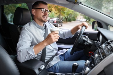 Photo of Man with cup of coffee driving modern car