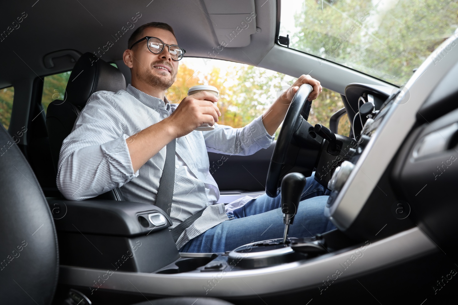 Photo of Man with coffee driving modern car, low angle view