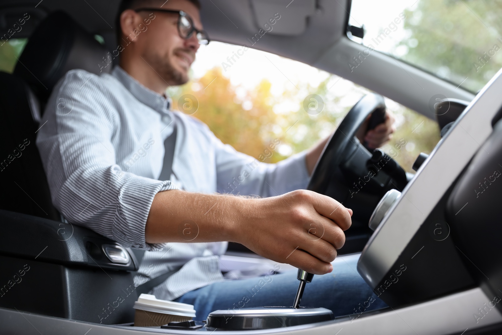 Photo of Man driving modern car, focus on gear stick