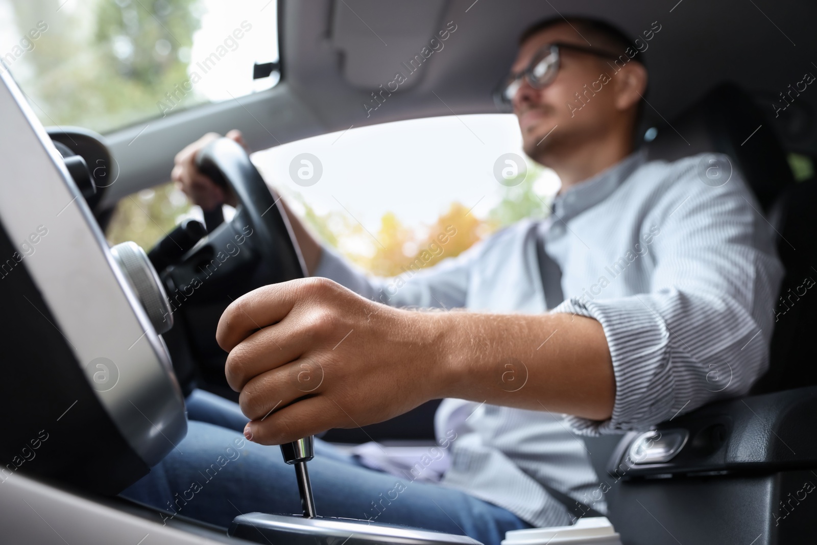 Photo of Man driving modern car, focus on gear stick