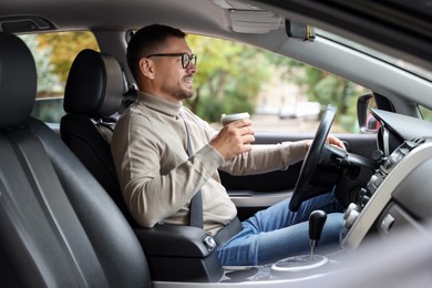 Photo of Man with cup of coffee driving modern car