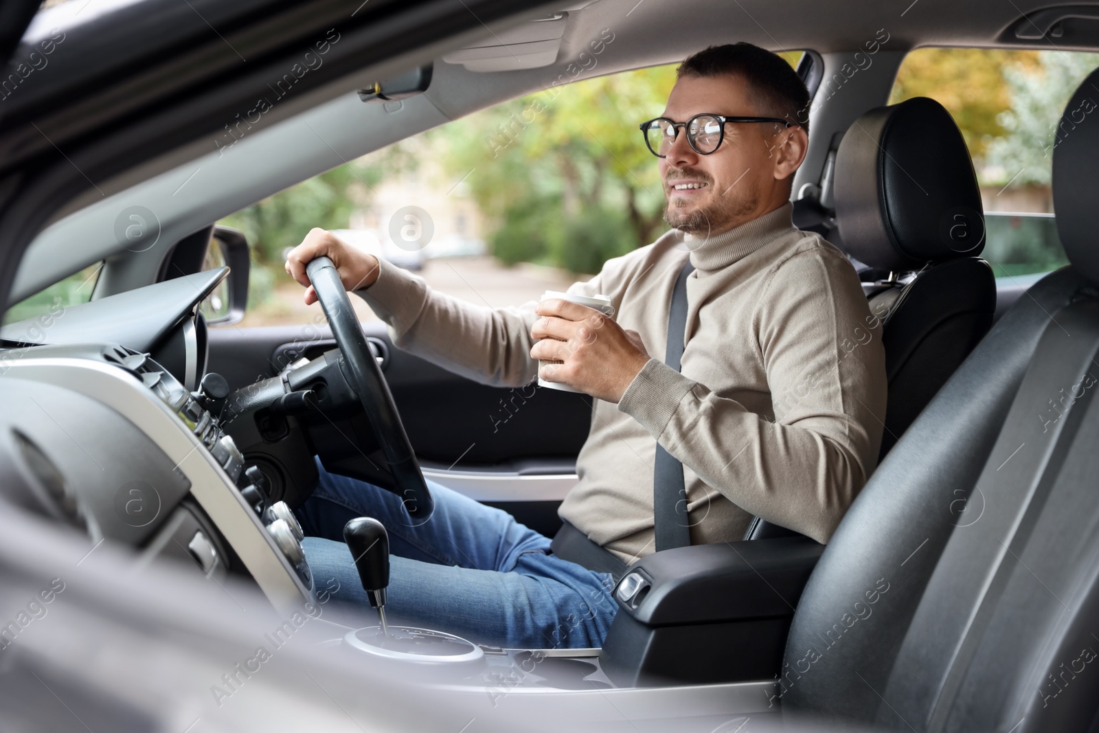 Photo of Man with cup of coffee driving modern car