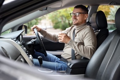 Photo of Man with cup of coffee driving modern car