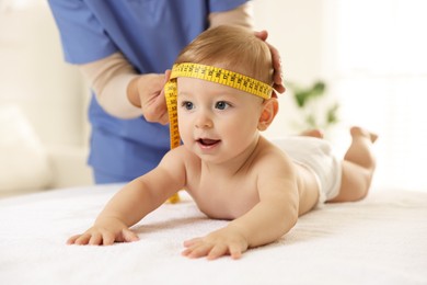 Photo of Pediatrician measuring little baby's head in clinic, closeup