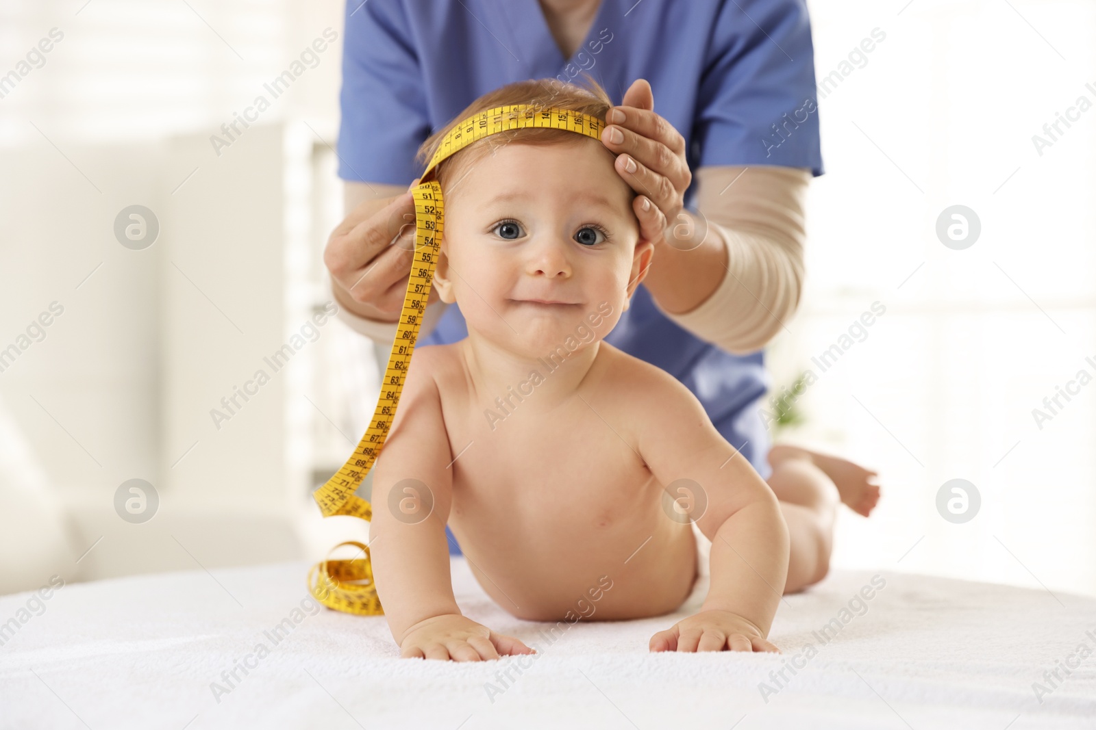 Photo of Pediatrician measuring little baby's head in clinic, closeup