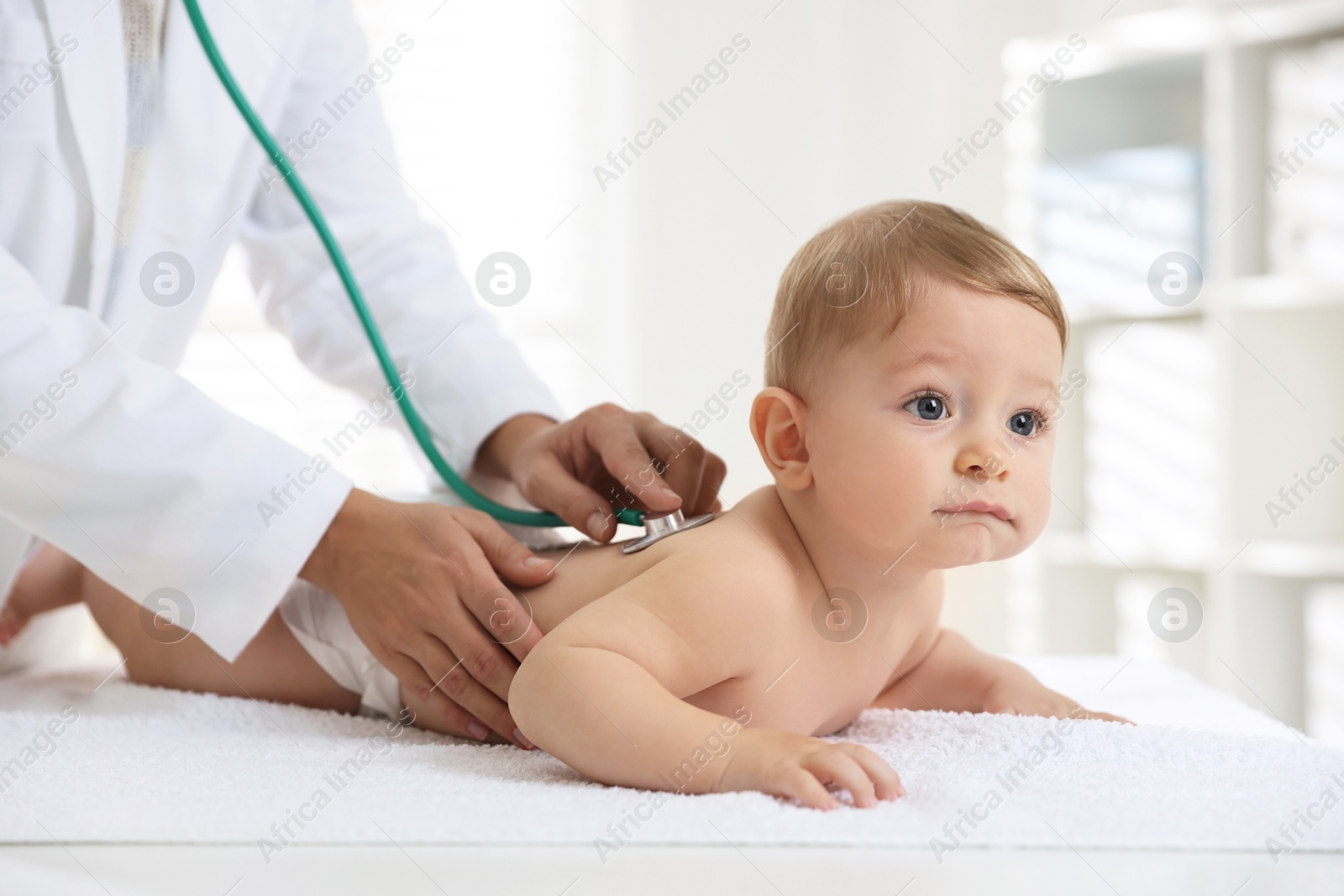 Photo of Pediatrician examining little child with stethoscope in clinic, closeup. Checking baby's health