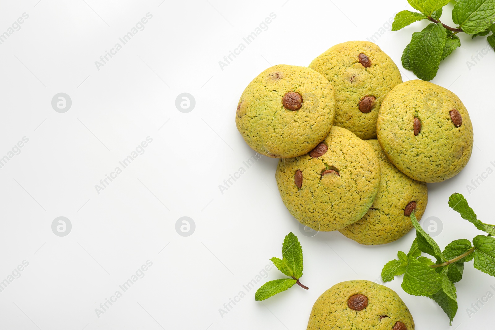 Photo of Delicious chocolate chip cookies and mint leaves on white table, flat lay. Space for text