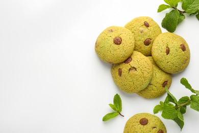 Photo of Delicious chocolate chip cookies and mint leaves on white table, flat lay. Space for text